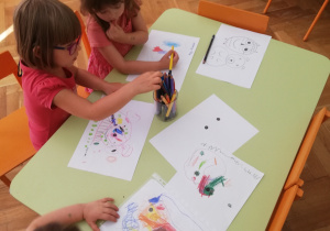 . Na zdjęciu-dzieci przy stolikach podczas rysowania kredkami na temat "Czym może być kropka?"